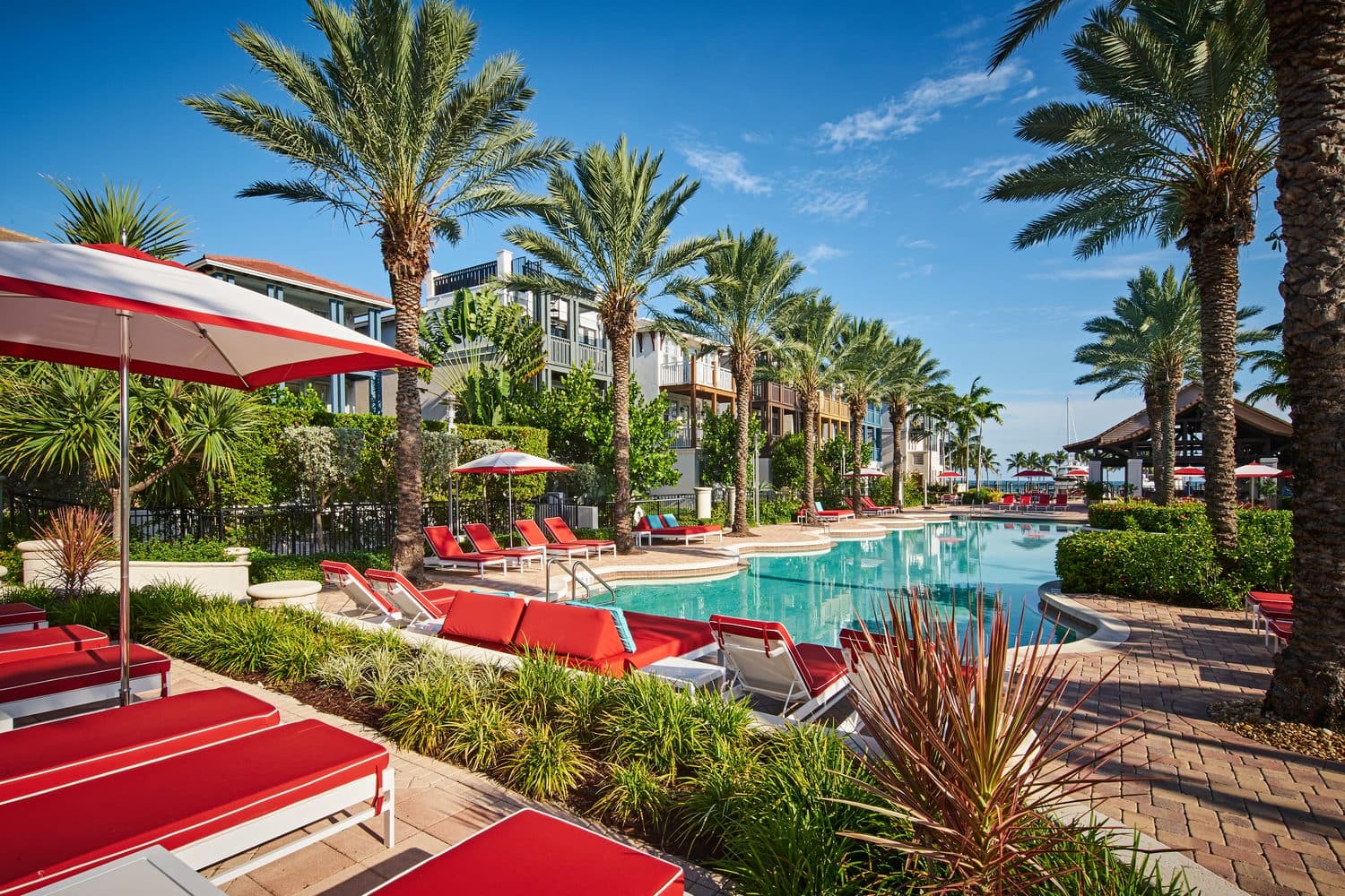 Beach-entry resort pool with red loungers and palm trees at Marlin Bay